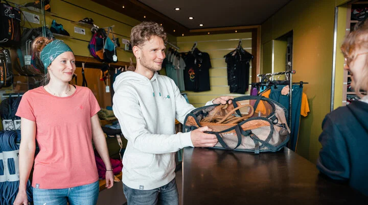 Zwei Personen leihen sich in einer Boulderhalle Ausrüstung aus. | © DAV/Marisa Koch